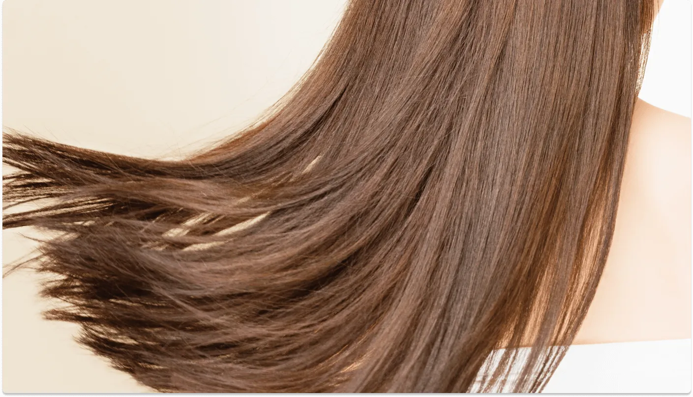 滑らかで美しい髪が風になびいている写真。髪質改善による健康的で艶やかな髪を示しています。