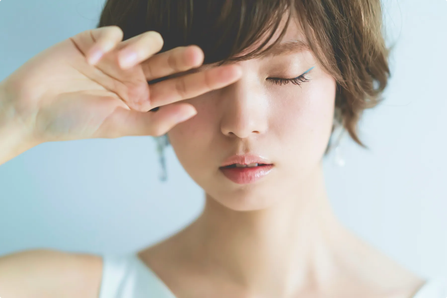 顔の前に手をかざして目を閉じた女性